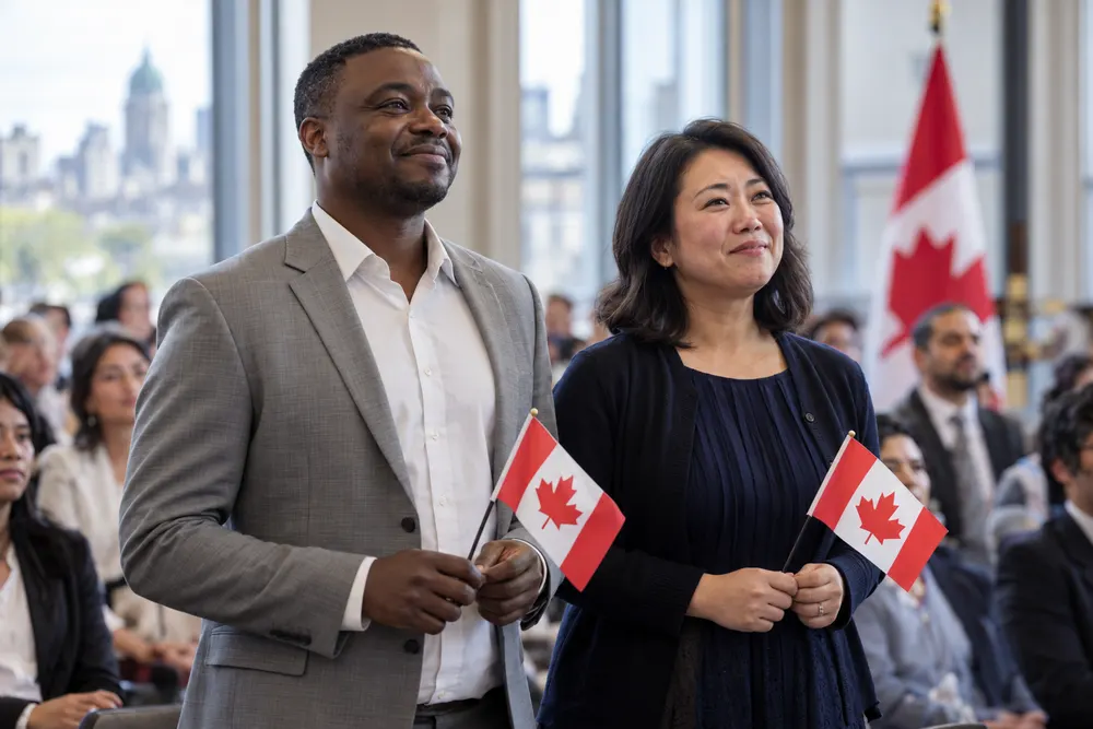 Nouveaux citoyens canadiens, un homme et une femme, tenant de petits drapeaux du Canada lors d’une cérémonie de citoyenneté à Montréal