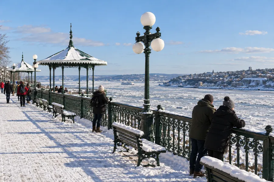 Terrasse Dufferin enneigée à Québec, des promeneurs regardent le fleuve chargé de glaces et Lévis