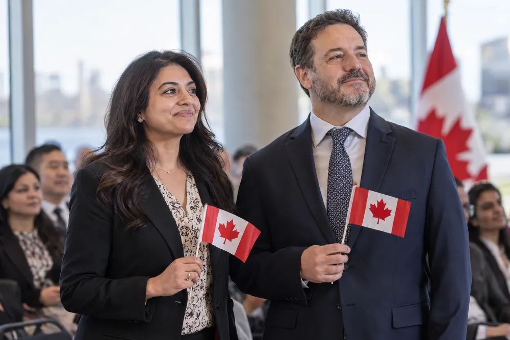 Nouveaux citoyens canadiens, une femme et un homme, tenant de petits drapeaux du Canada lors d’une cérémonie de citoyenneté